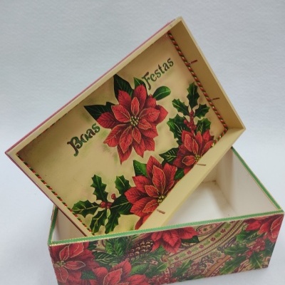 Caixa decorativa com padrão de flores vermelhas e folhas verdes, 'Boas Festas' na tampa.