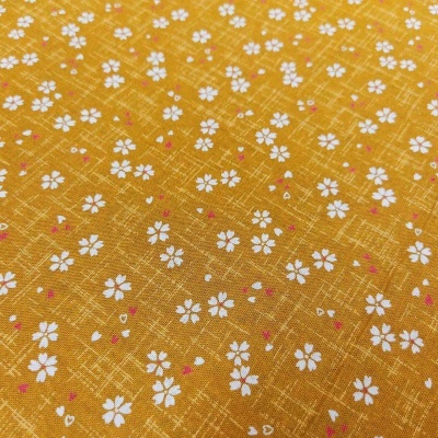 tecido amarelo com flores brancas pequenas e detalhes cor de rosa