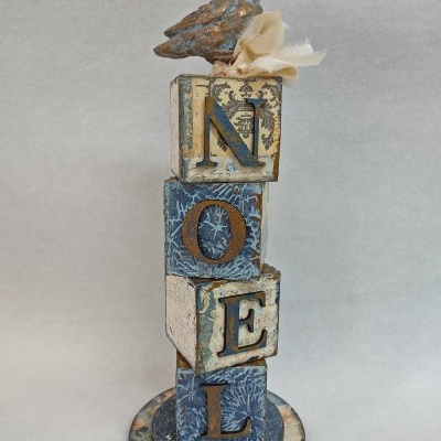 Escultura decorativa com blocos de madeira e pássaro no topo