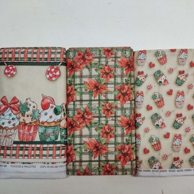 Três panos de cozinha com motivos de Natal, incluindo cupcakes e flores, em padrões coloridos.