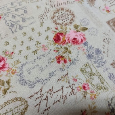 Tecido bege com padrão floral rosa e inscrições em francês.