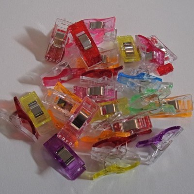 Ganchos de plástico coloridos com partes metálicas sobre fundo branco