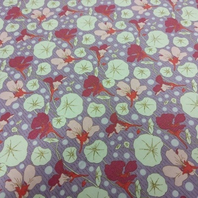 Tecido com padrão floral em fundo roxo com flores e folhas em verde e vermelho