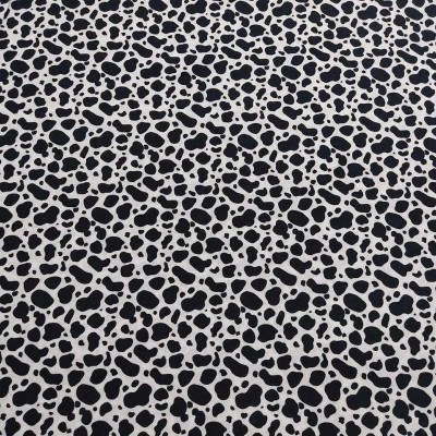 Tecido estampado com padrão de manchas pretas sobre fundo branco