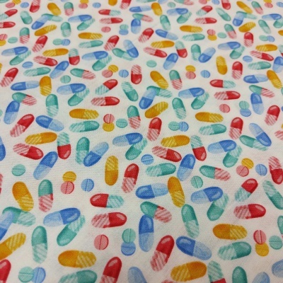 Tecido branco com padrão colorido de cápsulas e comprimidos.