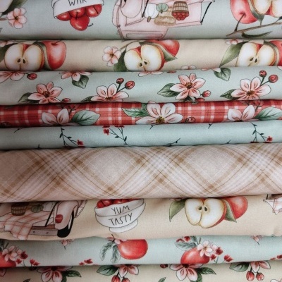 Tecidos dobrados coloridos com padrões de maçãs, flores e xadrez