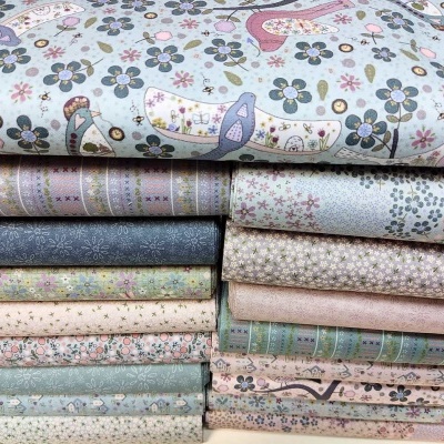 Pilha de tecidos estampados em padrões florais, animais e listras em cores suaves