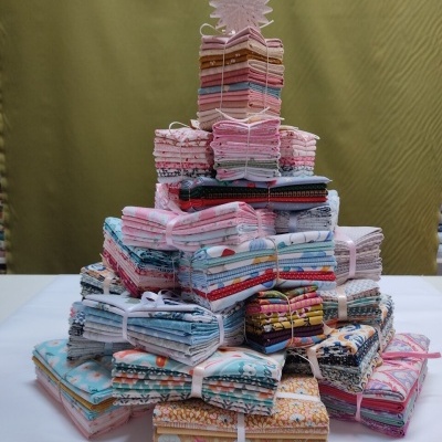 Pilha de tecidos coloridos dobrados e amarrados em formato de pirâmide sobre mesa branca.