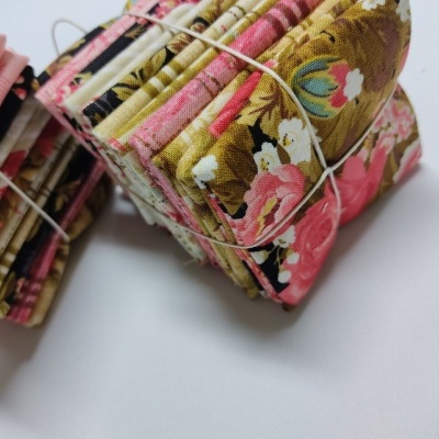 Pedaços de tecido com padrões florais coloridos amarrados com elásticos em fundo branco