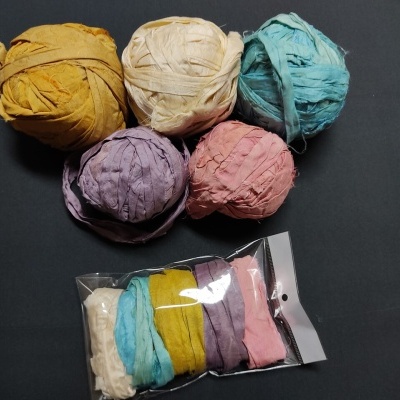 Bolas de fios coloridos e pacote plástico com fitas de tecido diversas cores sobre fundo preto