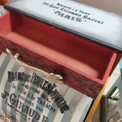 Caixa de madeira decorativa com tampa aberta e texto em francês.