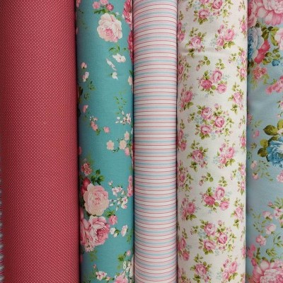 Rolos de tecido coloridos com padrões de riscas, pontos e flores.