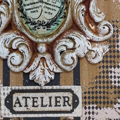 Placa decorativa envelhecida com texto 'ATELIER' em fundo quadriculado e riscas