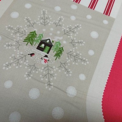 tecido natalício com casa, árvores e floco de neve em fundo bege com pontos brancos e bordas vermelhas