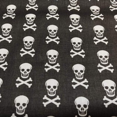 Tecido preto com padrão de caveiras e ossos cruzados brancos