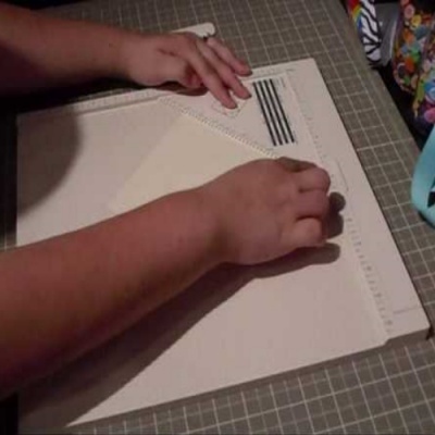 Pessoa usando régua transparente sobre tapete de corte branco com marcações de medição.