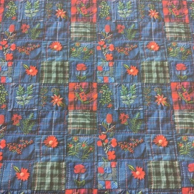 Tecido com padrão xadrez azul e verde com flores vermelhas e laranja