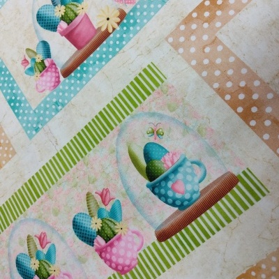 Pano de mesa com padrão de bolinhas e quadros decorativos de cactos em canecas coloridas