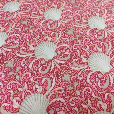 Tecido estampado rosa com conchas brancas e padrões decorativos vermelhos