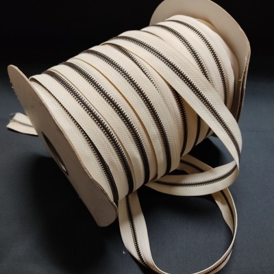 Rolo com tiras de correr bege com dentes metálicos escuros