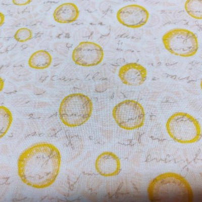 Tecido com padrão de círculos amarelos e texto manuscrito castanho claro