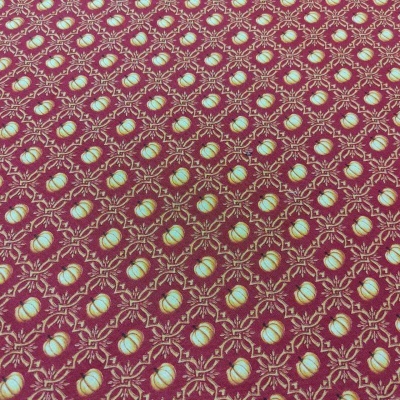 Tecido vermelho com padrão repetido de abóboras azuis e folhas douradas