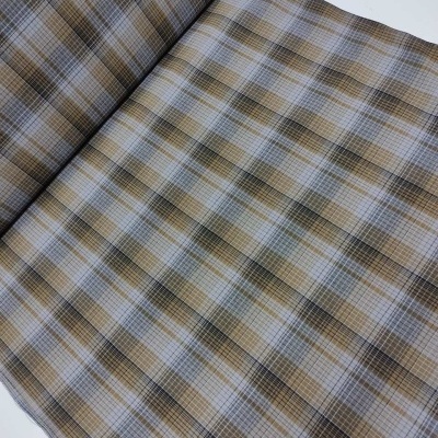 Tecido xadrez bege, branco, preto e cinza aberto sobre superfície branca