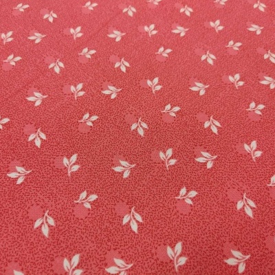 tecido cor-de-rosa com padrão de folhas brancas e pontos vermelhos