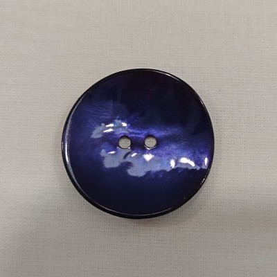 Botão azul escuro com dois furos sobre tecido claro