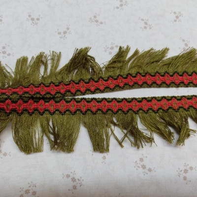 Franja têxtil verde com padrão vermelho e preto sobre fundo floral branco