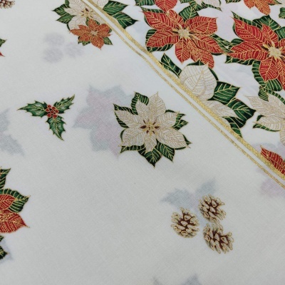 Tecido branco decorado com flores de natal vermelhas e douradas, folhas verdes e pinhas castanhas.