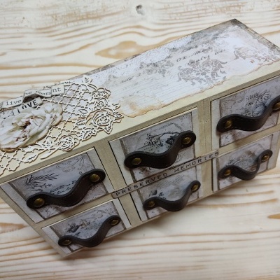 Móvel organizador de madeira com seis gavetas decoradas e puxadores de metal escuro