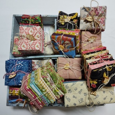 Tecidos coloridos e padrão variados dobrados e amarrados organizados em caixas de madeira.