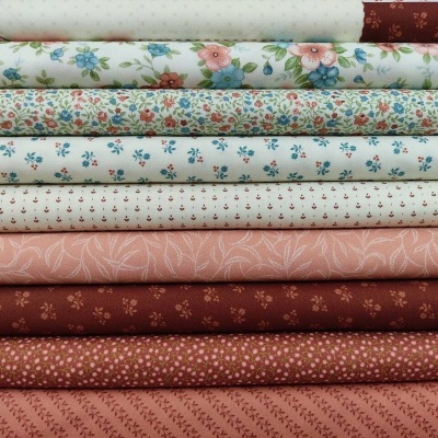 Tecidos empilhados com padrões florais e em tons castanhos, rosa, azul e creme