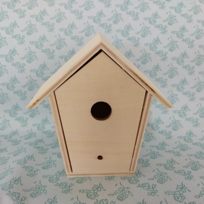 Casa de madeira para pássaros com fundo floral verde.