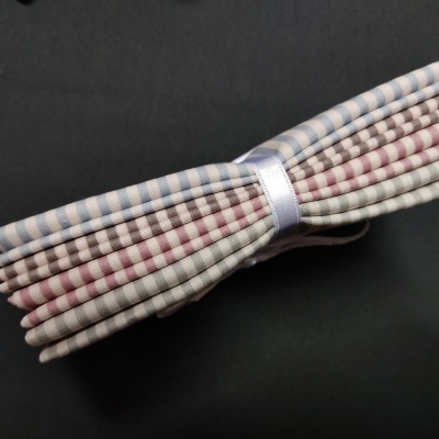 Laço feito de tecido xadrez azul, vermelho e bege, com fita prateada sobre fundo preto