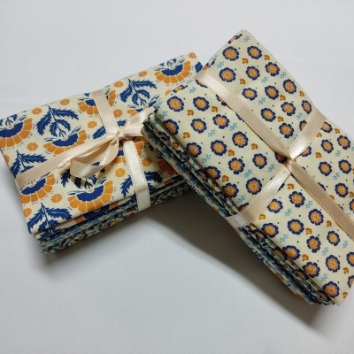 Conjuntos de tecidos florais azuis e amarelos dobrados e amarrados com fita creme