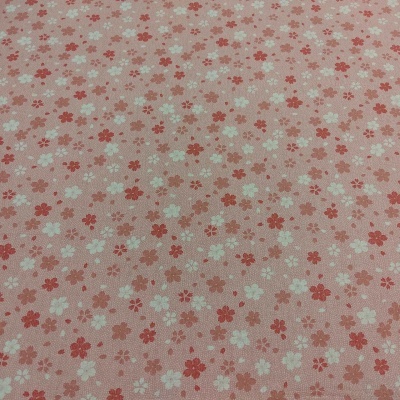 Tecido rosa com padrão de pequenas flores vermelhas e brancas.