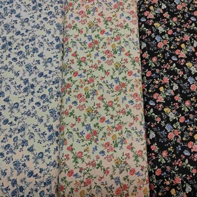 Tecidos florais em azul, creme e preto com padrões pequenos e multicoloridos