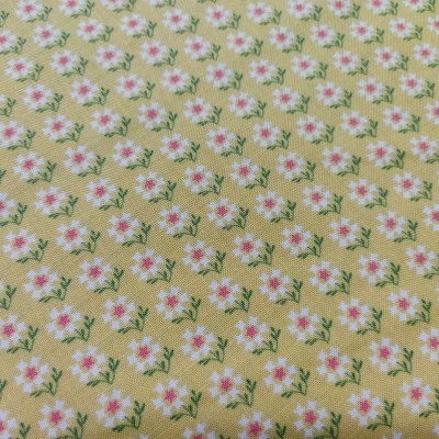 Tecido amarelo com padrão de pequenas flores brancas e folhas verdes