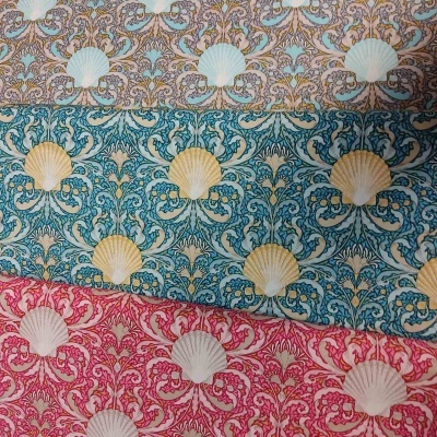Três tecidos com padrão de conchas e folhas em cores bege, azul-turquesa e rosa