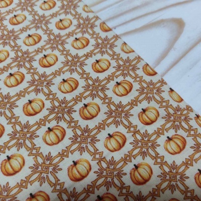 Tecido com padrão de abóboras e folhas em tons de laranja e castanho