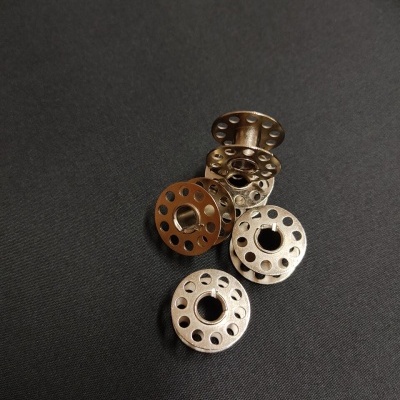 Cinco bobinas metálicas de máquina de costura sobre fundo preto