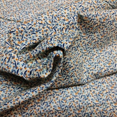 tecido estampado com padrão de ramos e folhas em azul e laranja