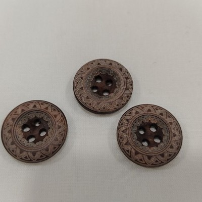 Três botões redondos castanhos com padrão gravado e quatro furos no centro