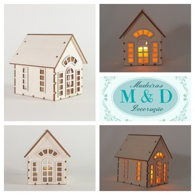 Casa decorativa em madeira com janelas iluminadas e logo Madeiras M&D Decoração