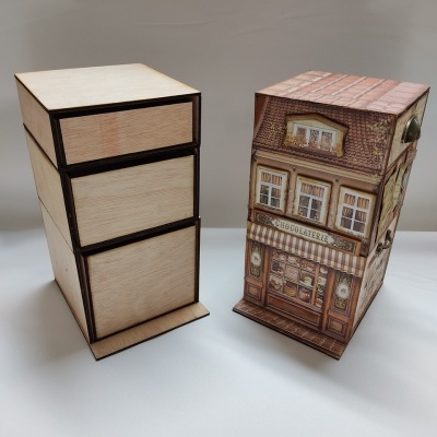 Duas caixas de armazenamento, uma em madeira clara com gavetas e outra em forma de casa com design de loja de chocolate.