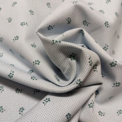 Tecido branco com pequenas flores verdes e textura perfurada