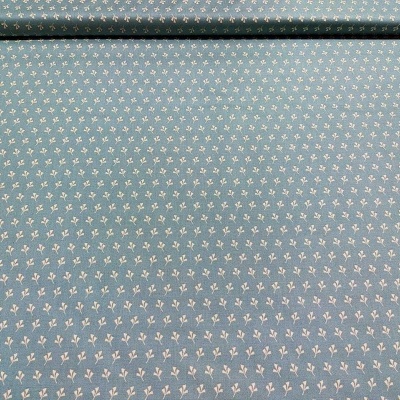 Tecido azul claro com padrão de pequenas flores brancas e folhas, parcialmente enrolado