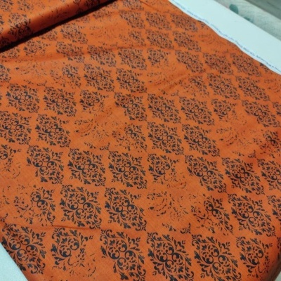 Tecido laranja com padrão preto de ornamentos florais em losangos